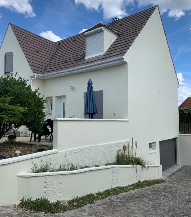 Maison moderne à deux étages avec un parasol bleu et un jardin.